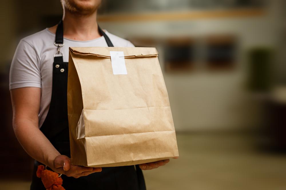 diverse of paper containers for takeaway food. delivery man is carrying